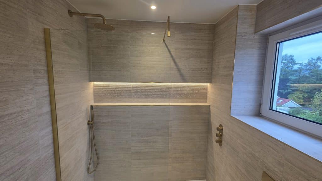 Walk-in shower in a Bearsden bathroom with brushed brass rain head, glass screen and LED-lit niche