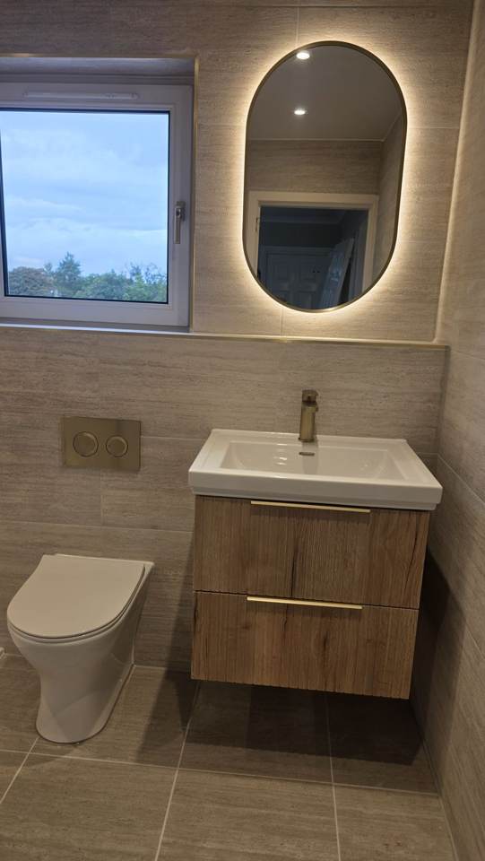 Wall-hung oak vanity with brushed brass tap and illuminated oval mirror in a Bearsden bathroom